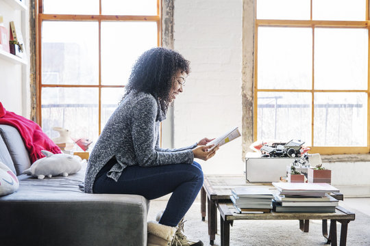 Side view of smiling businesswoman reading document while sitting in office
