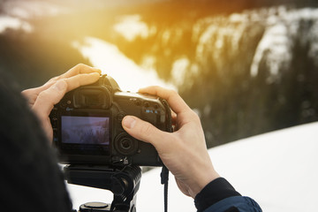 Cropped image of man photographing through digital camera on snowcapped mountain