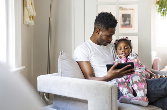 Father and daughter using tablet while sitting at home