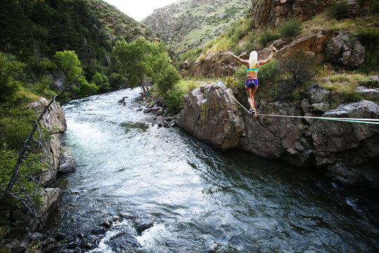 Rear view of woman slacklining over river against mountains