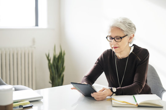 Mature Woman Using Digital Tablet While Sitting In Office