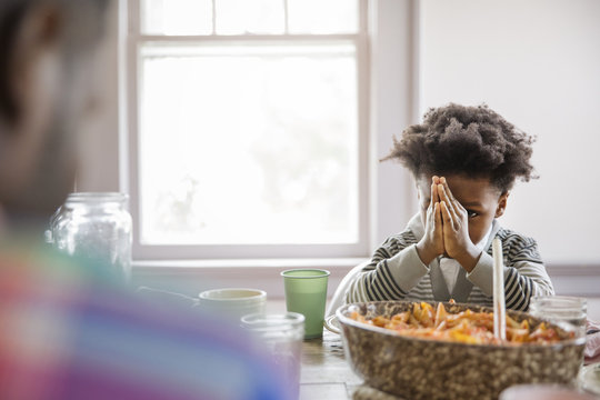 Boy looking at father while praying at dining table