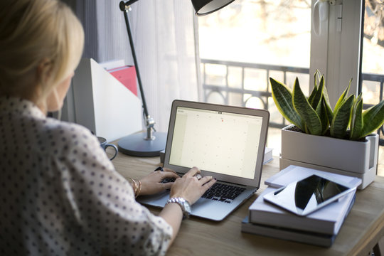 Rear View Of Woman Using Laptop At Home Office