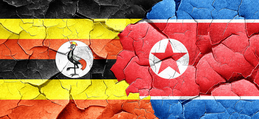 Uganda flag with North Korea flag on a grunge cracked wall