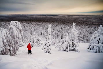 Man hiking on snow covered mountain against cloudy sky