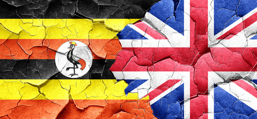 Uganda flag with Great Britain flag on a grunge cracked wall