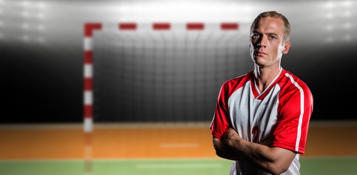 Portrait of volleyball player with arms crossed against digital image of handball goal 