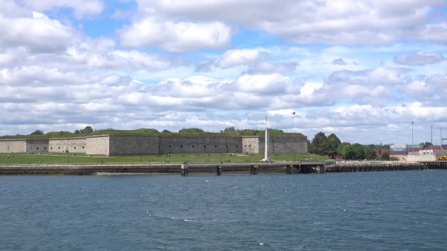 A daytime establishing shot of Castle Island Park in Boston as seen from the harbor.  	