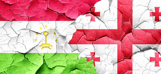 Tajikistan flag with Georgia flag on a grunge cracked wall