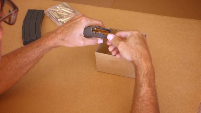 A man removes unused bullets from an AR15 magazine.  	