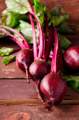 Organic young beets with green leaves on wooden table