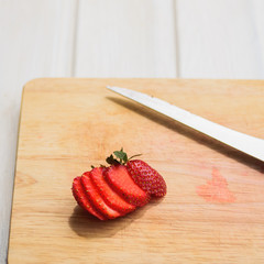 sliced strawberry on natural color wooden cutting board