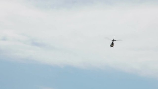 Helicopter Flying Overhead And Away In Blue Sky With With Clouds