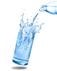 Pouring water from bottle into glass with splashing. Isolated on white background.