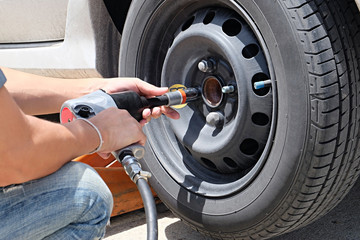 Man is changing tire with wheel wrench. Auto mechanic changing car wheel