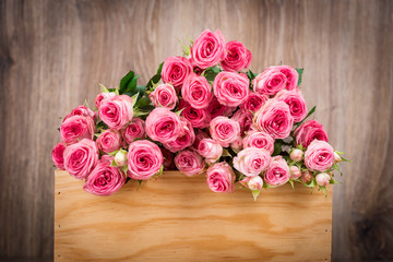 Roses in the box on wooden background