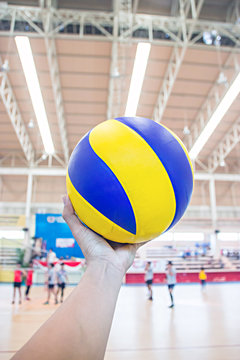 left hand holds a volleyball
