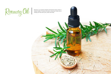 a bottle of rosemary aromatherapy oil extract with fresh and dried rosemary leaf on wooden spoon.  © mamsizz