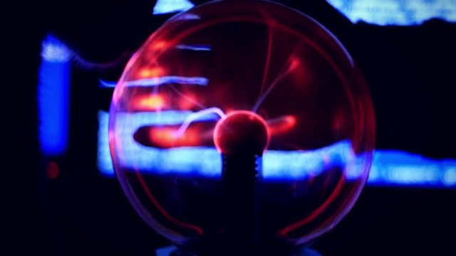 Plasma Ball - a transparent sphere filled with rarefied inert gas. Slowmotion of Hand touch the plasma ball against a blue background broken computer and near  sitting cat
