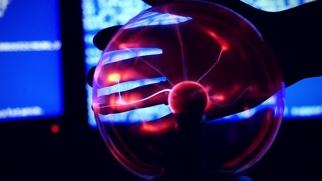 Plasma Ball - a transparent sphere filled with rarefied inert gas. Slowmotion of Hand touch the plasma ball against a blue background broken computer