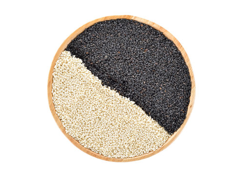 dried black and white sesame in wooden plate on white background