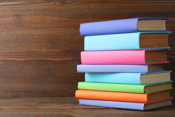 a stack of books in beautiful covers on wooden background