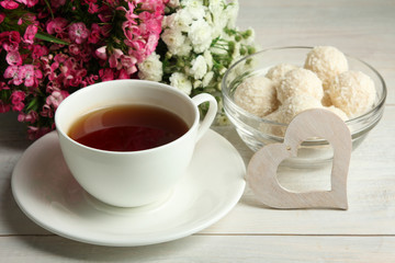 white decorative hearts with candy and chrysanthemum on white wooden background with Cup of tea