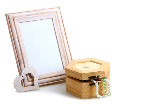 open wooden box with beads near the wooden photo frames and decorative heart on a white isolated background