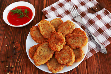 Fried potato pancakes and tomato sauce on the wooden background