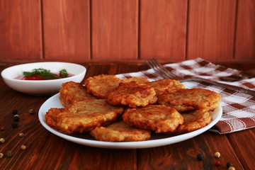 Fried potato pancakes and tomato sauce on the brown wooden table