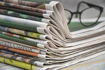 Close-up of a stack of colored papers with black glasses on a wooden table background