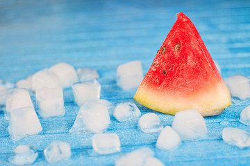 Slice watermelon and with ice Cube on blue background