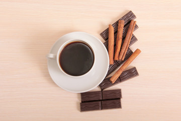 Coffee cup and chocolate on wood background