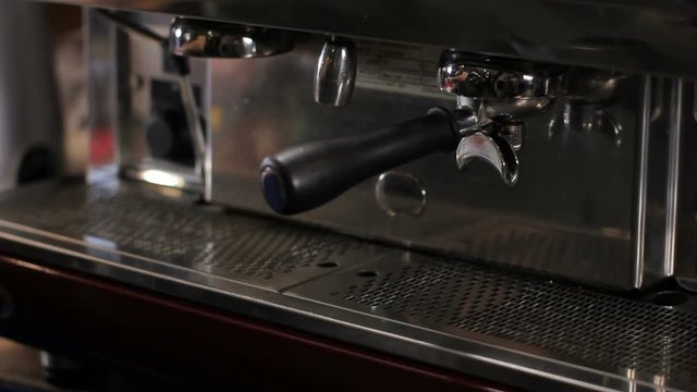 Barista picks up two cups of fresh made espresso. Medium shot