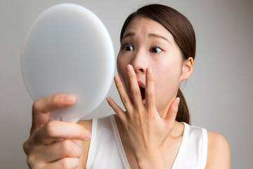鏡を見て驚く女性