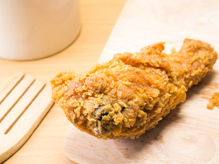 fried chicken on a chopping broad with a glass set on a wood background