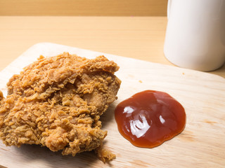 fried chicken on a chopping broad with a tomato sause set on a wood background
