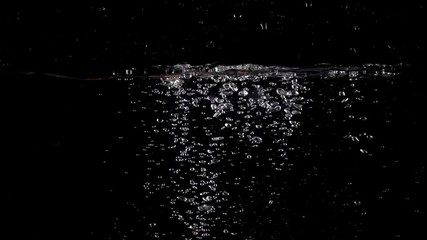 Slow motion shot of tomatoes falling and floating in water, black background - Powered by Adobe