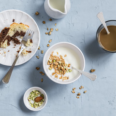 Breakfast - greek yogurt with granola and pistachios, chocolate cake and coffee. On a blue stone background