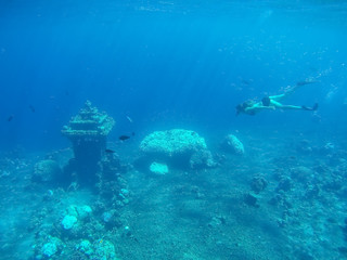 Underwater shot of the woman moving on the breath hold in the depth. Amed village, Bali, Indonesia