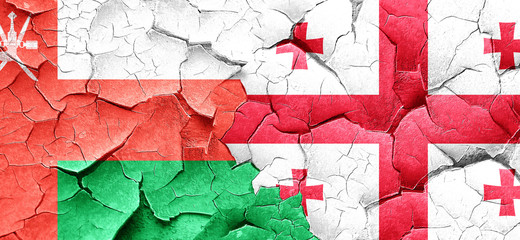 Oman flag with Georgia flag on a grunge cracked wall