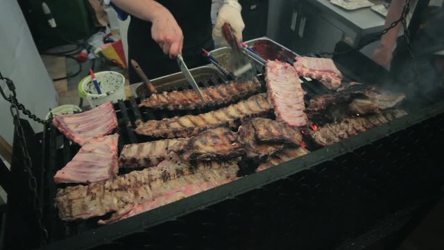 BBQ Ribs on the grill. Cook prepares meat, check availability.