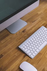 Top view of a computer monitor with a blank screen on a pure white background of a brick wall and a keyboard and mouse on a wooden table, blank for your text or content or design, closeup, free space