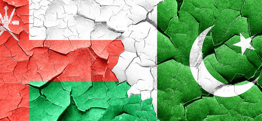 Oman flag with Pakistan flag on a grunge cracked wall