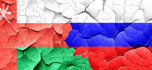 Oman flag with Russia flag on a grunge cracked wall