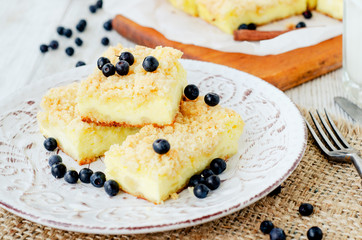 
rustic grated cheese cake with berries , with blueberries and milk on a wooden background