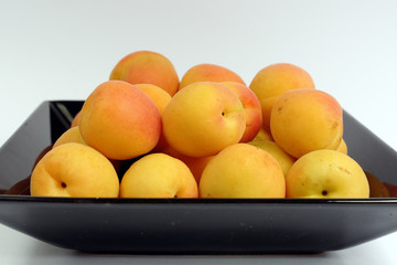 Ripe apricots on a black plate