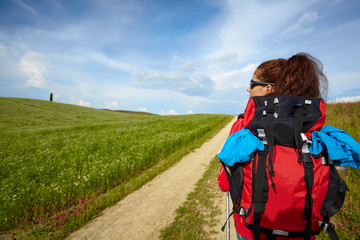 Tourist woman with backpack hiking in the mountains on field