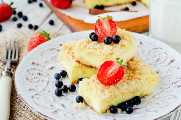 
rustic grated cheese cake with berries , with strawberries , blueberries and milk on a wooden background