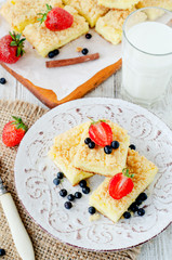 
rustic grated cheese cake with berries , with strawberries , blueberries and milk on a wooden background